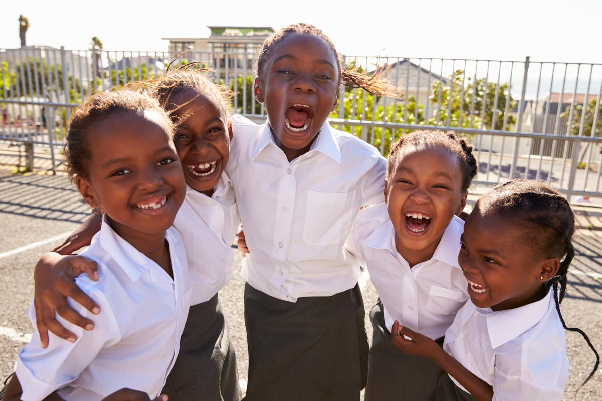 Young African schoolgirls in playground smiling